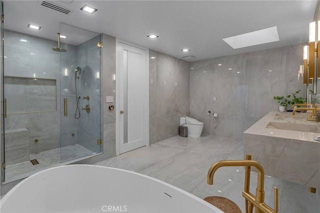 15125 Rayneta Dr, Sherman Oaks, CA 91403 - full bathroom featuring a skylight, a marble finish shower, a freestanding bath, double vanity, and tile walls