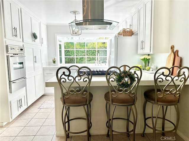 26261 Veva Way, Calabasas, CA 91302 - kitchen with stainless steel oven, a warming drawer, island exhaust hood, white cabinets, and a kitchen bar
