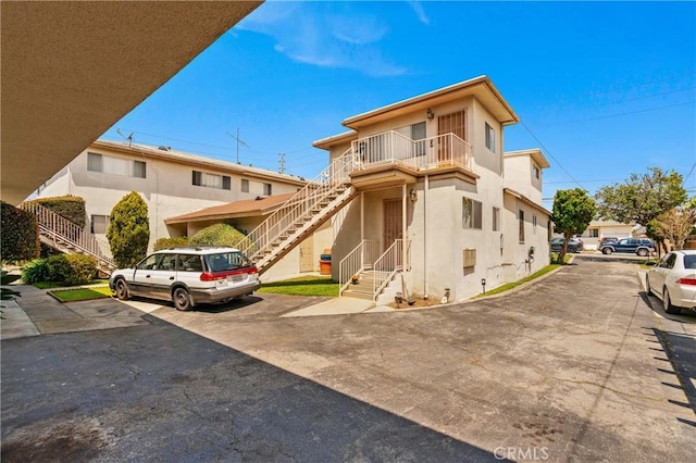 1900 Vanderbilt Ln, Redondo Beach, CA 90278 - view of front facade with stairway, stucco siding, and uncovered parking