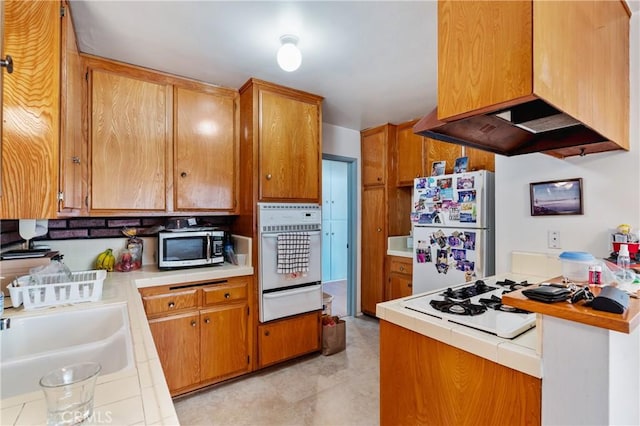 1900 Vanderbilt Ln, Redondo Beach, CA 90278 - kitchen featuring white appliances, a warming drawer, tile counters, ventilation hood, and brown cabinets
