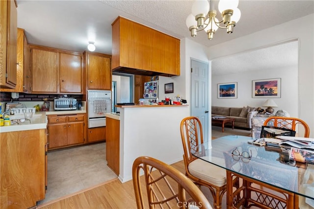 1900 Vanderbilt Ln, Redondo Beach, CA 90278 - kitchen featuring brown cabinets, a chandelier, stainless steel microwave, light countertops, and a warming drawer