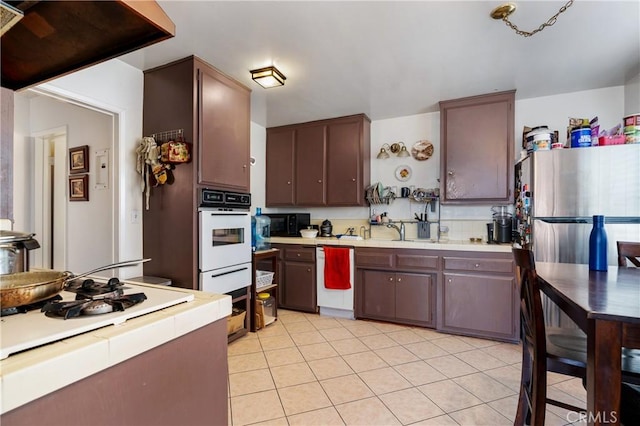 1900 Vanderbilt Ln, Redondo Beach, CA 90278 - kitchen featuring white appliances, tile counters, light tile patterned floors, a warming drawer, and dark brown cabinets