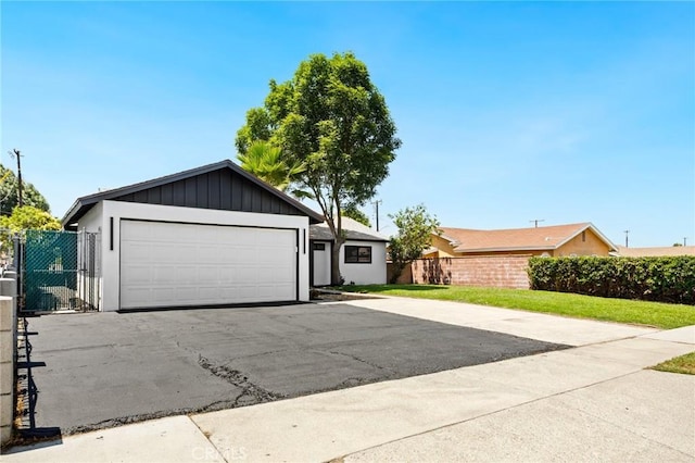 4883 Harvard St, Montclair, CA 91763 - ranch-style home featuring asphalt driveway, an attached garage, and board and batten siding