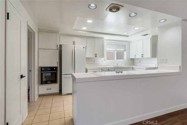 2343 Navarro Dr, Claremont, CA 91711 - kitchen featuring black appliances, light countertops, a peninsula, white cabinetry, and a tray ceiling