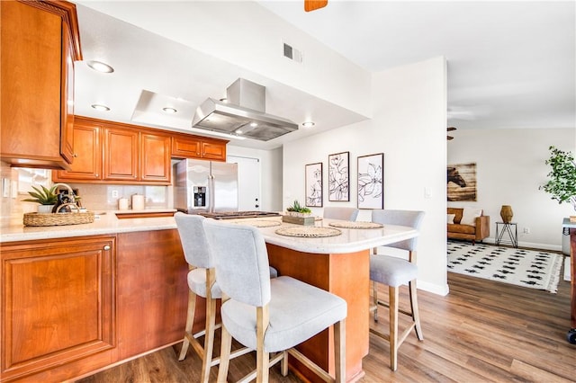 8761 Sandhill Dr, Riverside, CA 92508 - kitchen featuring stainless steel refrigerator with ice dispenser, exhaust hood, light wood-style floors, a peninsula, and brown cabinetry
