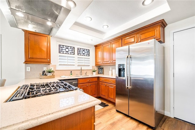 8761 Sandhill Dr, Riverside, CA 92508 - kitchen featuring stainless steel appliances, wall chimney range hood, a tray ceiling, light wood finished floors, and recessed lighting
