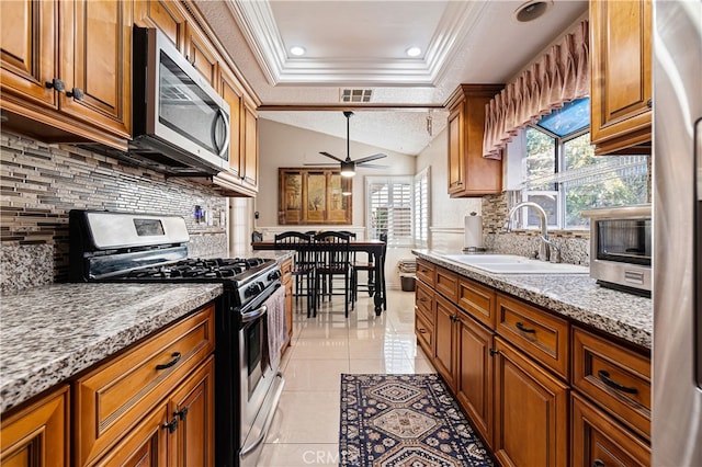 3718 Berkshire Rd, Pico Rivera, CA 90660 - kitchen featuring appliances with stainless steel finishes, a raised ceiling, brown cabinetry, tasteful backsplash, and crown molding