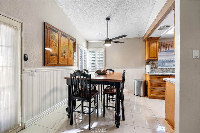 3718 Berkshire Rd, Pico Rivera, CA 90660 - dining space with a textured ceiling, a ceiling fan, a wainscoted wall, and light tile patterned floors