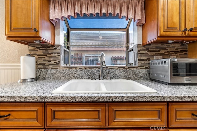 3718 Berkshire Rd, Pico Rivera, CA 90660 - kitchen featuring brown cabinets, backsplash, a wainscoted wall, and a textured wall