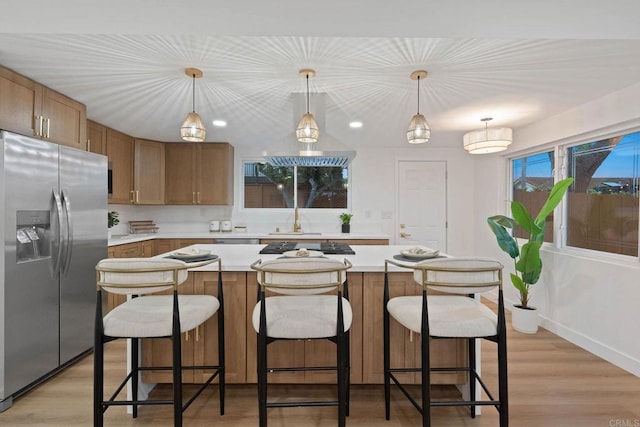 709 Puebla St, Encinitas, CA 92024 - kitchen featuring stainless steel fridge with ice dispenser, light countertops, light wood-style floors, a kitchen bar, and decorative light fixtures
