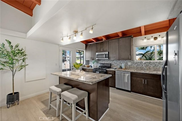 15352 Pastrana Dr, La Mirada, CA 90638 - kitchen with stainless steel appliances, light wood-style flooring, a kitchen island, decorative backsplash, and a kitchen breakfast bar