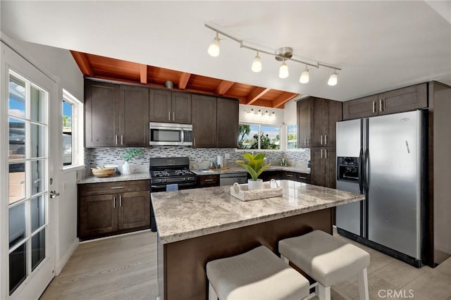 15352 Pastrana Dr, La Mirada, CA 90638 - kitchen featuring stainless steel appliances, dark brown cabinets, a kitchen breakfast bar, and backsplash