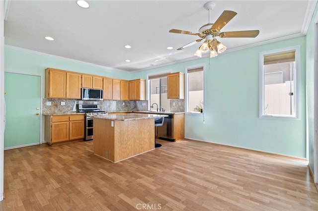 23832 Matador Way, Murrieta, CA 92562 - kitchen featuring stainless steel appliances, crown molding, a kitchen island, tasteful backsplash, and light wood-style flooring