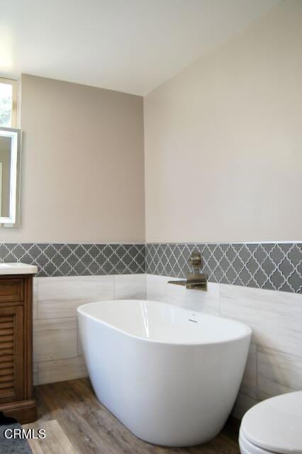 691 Via Ondulando, Ventura, CA 93003 - bathroom featuring tile walls, vanity, a soaking tub, wainscoting, and wood finished floors