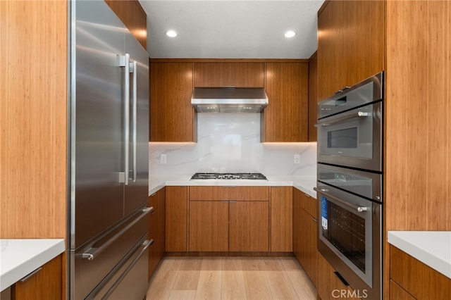 325 N Madison Ave, Monrovia, CA 91016 - kitchen featuring stainless steel appliances, ventilation hood, brown cabinetry, light countertops, and light wood finished floors