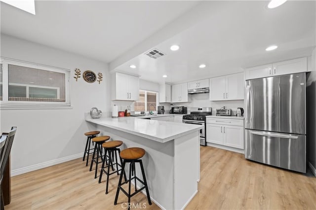 18536 Mescal St, Rowland Heights, CA 91748 - kitchen with appliances with stainless steel finishes, under cabinet range hood, a kitchen bar, a peninsula, and light wood finished floors