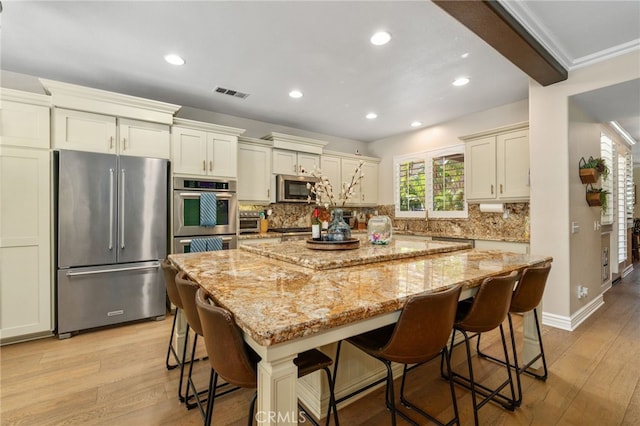 14131 Apple Grove Ct, Eastvale, CA 92880 - kitchen featuring stainless steel appliances, light wood-type flooring, decorative backsplash, light stone counters, and recessed lighting