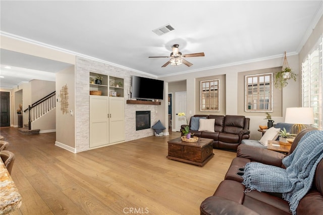 14131 Apple Grove Ct, Eastvale, CA 92880 - living area featuring light wood-style floors, a stone fireplace, built in features, ornamental molding, and ceiling fan