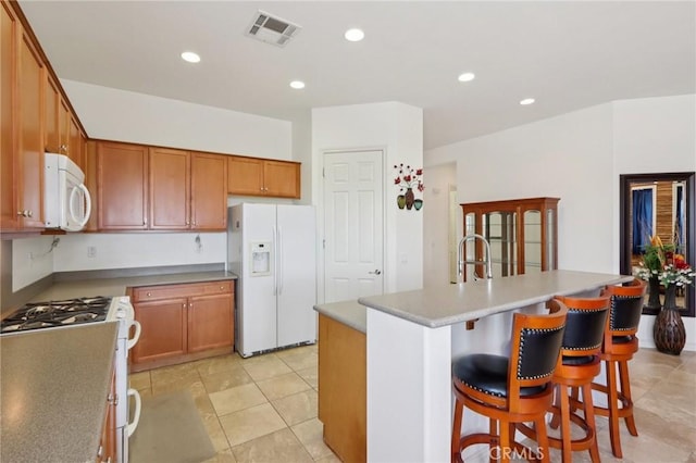 1627 Camino Sueno, Hemet, CA 92545 - kitchen with white appliances, recessed lighting, brown cabinetry, a kitchen breakfast bar, and a kitchen island with sink