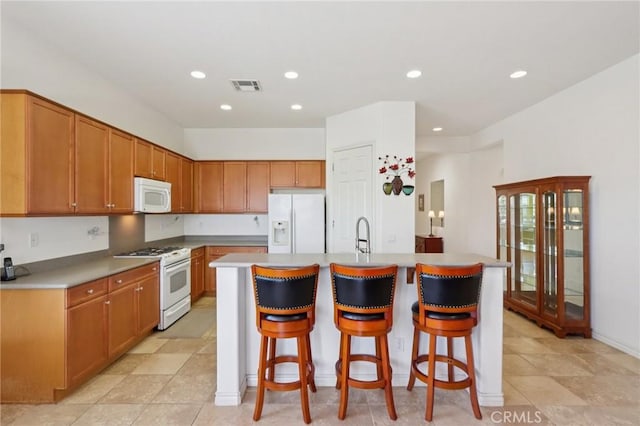 1627 Camino Sueno, Hemet, CA 92545 - kitchen with white appliances, a kitchen island with sink, a breakfast bar, recessed lighting, and light countertops