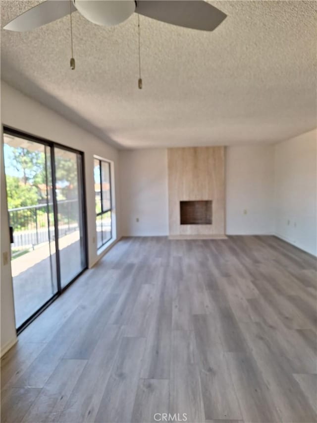 3144 Via Vis Unit Q, Laguna Woods, CA 92637 - unfurnished living room with a textured ceiling, wood finished floors, a large fireplace, and ceiling fan