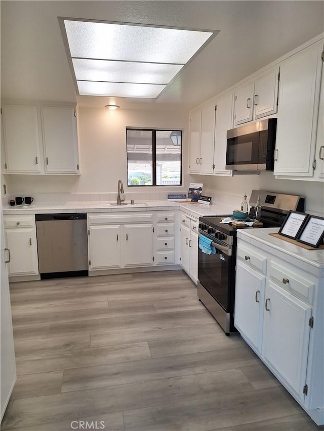 3144 Via Vis Unit Q, Laguna Woods, CA 92637 - kitchen featuring stainless steel appliances, white cabinetry, and light wood finished floors