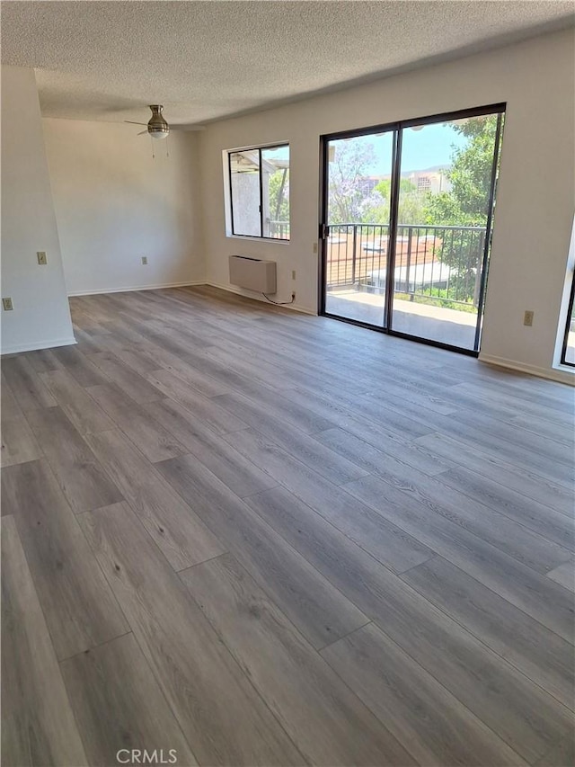 3144 Via Vis Unit Q, Laguna Woods, CA 92637 - spare room with a wall mounted air conditioner, a textured ceiling, wood finished floors, and a ceiling fan