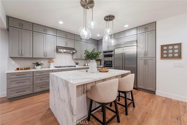 35 Beachcomber Dr, Corona Del Mar, CA 92625 - kitchen with gray cabinetry, stainless steel appliances, light stone counters, under cabinet range hood, and a kitchen island