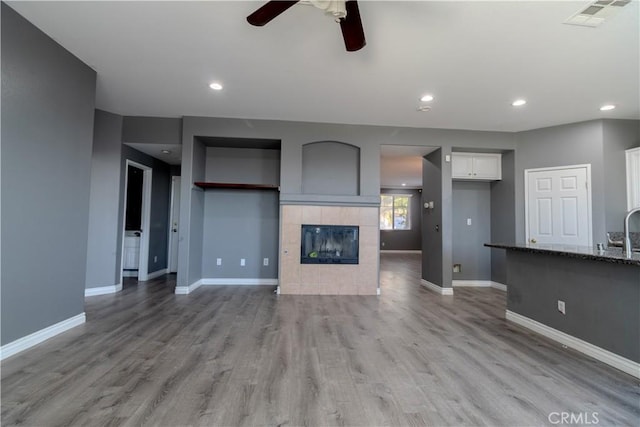 13740 Starshine Dr, Victorville, CA 92392 - unfurnished living room with a ceiling fan, light wood-style flooring, a tile fireplace, and recessed lighting