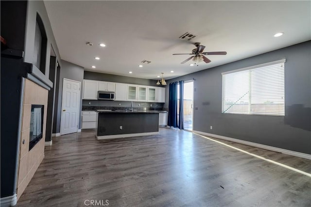 13740 Starshine Dr, Victorville, CA 92392 - kitchen with stainless steel microwave, dark countertops, white cabinetry, open floor plan, and recessed lighting