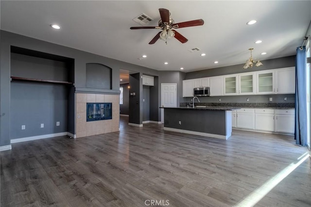13740 Starshine Dr, Victorville, CA 92392 - kitchen featuring stainless steel microwave, dark countertops, ceiling fan, a tiled fireplace, and white cabinets