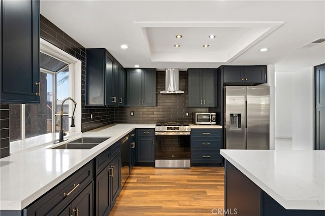 40132 White Leaf Ln, Murrieta, CA 92562 - kitchen featuring appliances with stainless steel finishes, wall chimney range hood, recessed lighting, a tray ceiling, and light wood-style floors