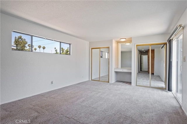 513 W D St, Wilmington, CA 90744 - unfurnished bedroom with two closets, multiple windows, carpet floors, and a textured ceiling