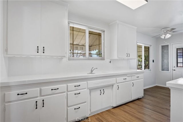 513 W D St, Wilmington, CA 90744 - kitchen featuring backsplash, ceiling fan, light countertops, light wood-style flooring, and white cabinetry