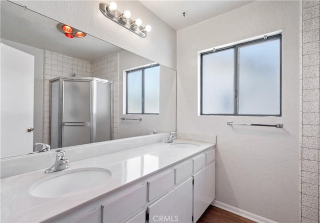 513 W D St, Wilmington, CA 90744 - bathroom featuring healthy amount of natural light, a stall shower, double vanity, and wood finished floors