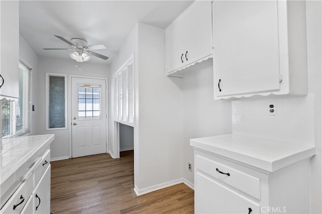 513 W D St, Wilmington, CA 90744 - kitchen with a ceiling fan, white cabinetry, light wood finished floors, decorative backsplash, and tile countertops