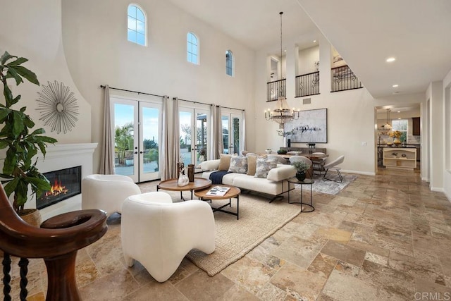 7603 Circulo Sequoia, Carlsbad, CA 92009 - living area with a high ceiling, stone tile floors, a glass covered fireplace, french doors, and a chandelier