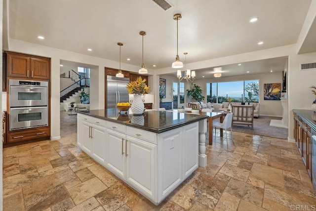 7603 Circulo Sequoia, Carlsbad, CA 92009 - kitchen featuring appliances with stainless steel finishes, stone tile floors, dark countertops, a kitchen island, and white cabinetry