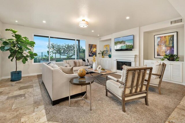 7603 Circulo Sequoia, Carlsbad, CA 92009 - living area with a glass covered fireplace, stone tile flooring, and recessed lighting