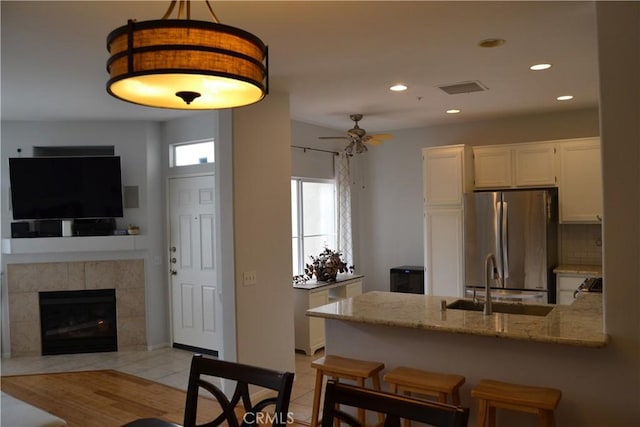 21 Veneto Ln, Aliso Viejo, CA 92656 - kitchen featuring freestanding refrigerator, a peninsula, light stone countertops, white cabinetry, and recessed lighting