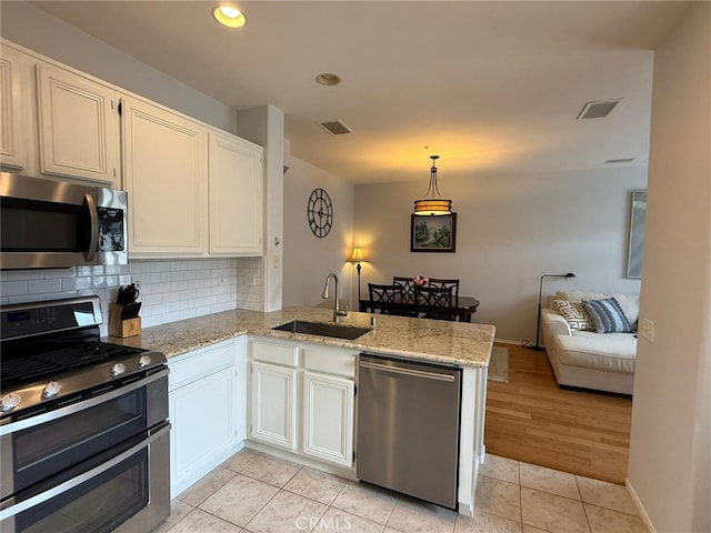 21 Veneto Ln, Aliso Viejo, CA 92656 - kitchen featuring stainless steel appliances, a peninsula, tasteful backsplash, light stone counters, and recessed lighting
