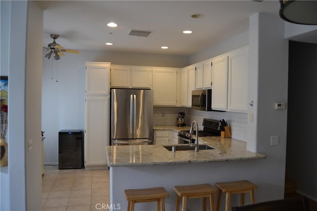 21 Veneto Ln, Aliso Viejo, CA 92656 - kitchen featuring stainless steel appliances, a peninsula, light stone counters, ceiling fan, and backsplash