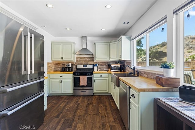 27763 Sequoia Glen Dr, Valencia, CA 91354 - kitchen featuring appliances with stainless steel finishes, wall chimney range hood, wooden counters, dark wood-style flooring, and decorative backsplash