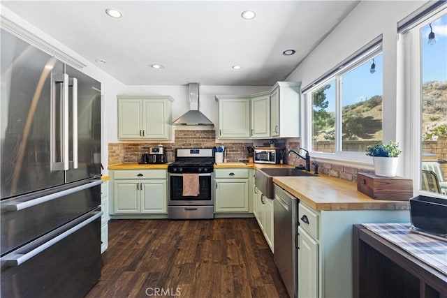 27763 Sequoia Glen Dr, Valencia, CA 91354 - kitchen featuring appliances with stainless steel finishes, wall chimney exhaust hood, wooden counters, dark wood finished floors, and backsplash