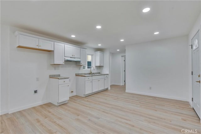 156 N Sunset Ave, Banning, CA 92220 - kitchen with under cabinet range hood, light wood finished floors, recessed lighting, and white cabinetry