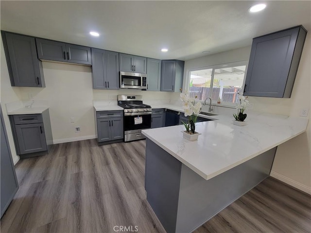 12922 Glenmere Dr, Moreno Valley, CA 92553 - kitchen featuring appliances with stainless steel finishes, a peninsula, gray cabinets, wood finished floors, and recessed lighting