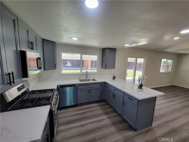 12922 Glenmere Dr, Moreno Valley, CA 92553 - kitchen featuring dishwashing machine, stainless steel range with gas cooktop, a peninsula, a textured ceiling, and dark wood-style floors