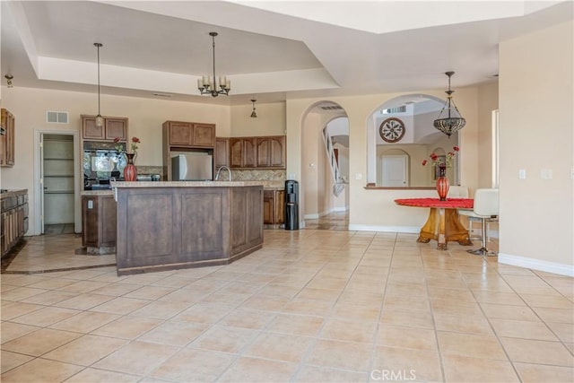 11110 Choctaw Dr, Bakersfield, CA 93308 - kitchen with fridge, arched walkways, a raised ceiling, light countertops, and light tile patterned floors