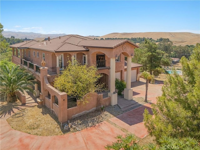 11110 Choctaw Dr, Bakersfield, CA 93308 - mediterranean / spanish house featuring concrete driveway, a mountain view, stucco siding, a balcony, and a tile roof
