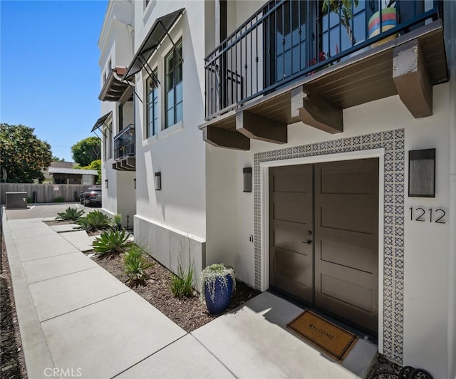 1212 Carmel St, San Luis Obispo, CA 93401 - view of exterior entry with a balcony, stucco siding, and a garage
